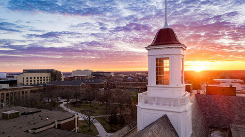 Aerial image of a sunrise over UNL's City Campus with the Love Library cupola in the foreground.
