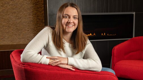 Abby Seibel sitting in red chair by fireplace