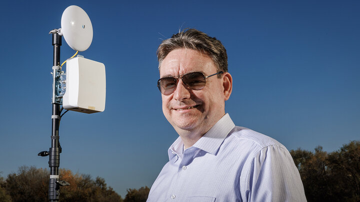 Mehmet Can Vuran lead member of the Field-Nets research team poses in a soybean field on east campus field with a Millimeter-wave (mmWave) radio with phased-array antennas.