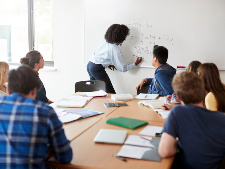 Female High School Tutor At Whiteboard Teaching Maths Class