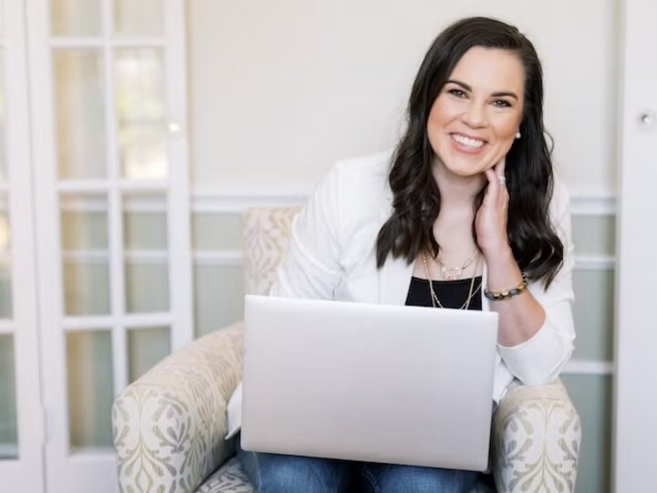 dr katelyn jetelina sitting i a chair with a laptop