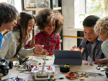 students group building robotic vehicle robot cars using tablet computer 