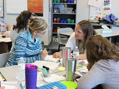 Teachers helping out each other as they work around a table