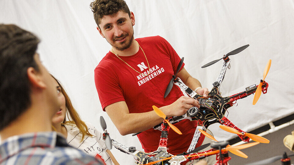 Student working on drone and showing with other students