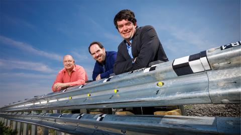 Husker researchers Cody Stolle (right), Josh Steelman (center) and Ronald Faller lean against a guardrail developed at the university-housed Midwest Roadside Safety Facility.