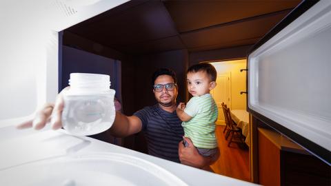Kazi Albab Hussain (left) holds his son while removing a plastic container of water from a microwave. Hussain and colleagues at the University of Nebraska–Lincoln have found that microwaving such containers can release up to billions of nanoscopic particles and millions of microscopic ones.