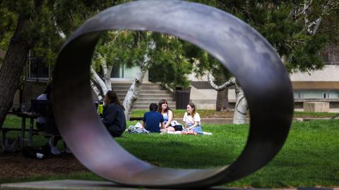 Framed by the sculpture Fragment X-O, Paige Vose (center), Makena Niehause and Evan Mott (back to camera) enjoy the sunshine and prefect spring weather at the Sheldon sculpture garden on April 17.