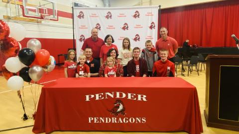 Caleb Kelly (seated, second from right) signed as the University of Nebraska–Lincoln's first Presidential Scholar on March 5. He celebrated the day with his family, friends and members of the university community, including Chris Kabourek (standing, far right), interim president of the NU system.